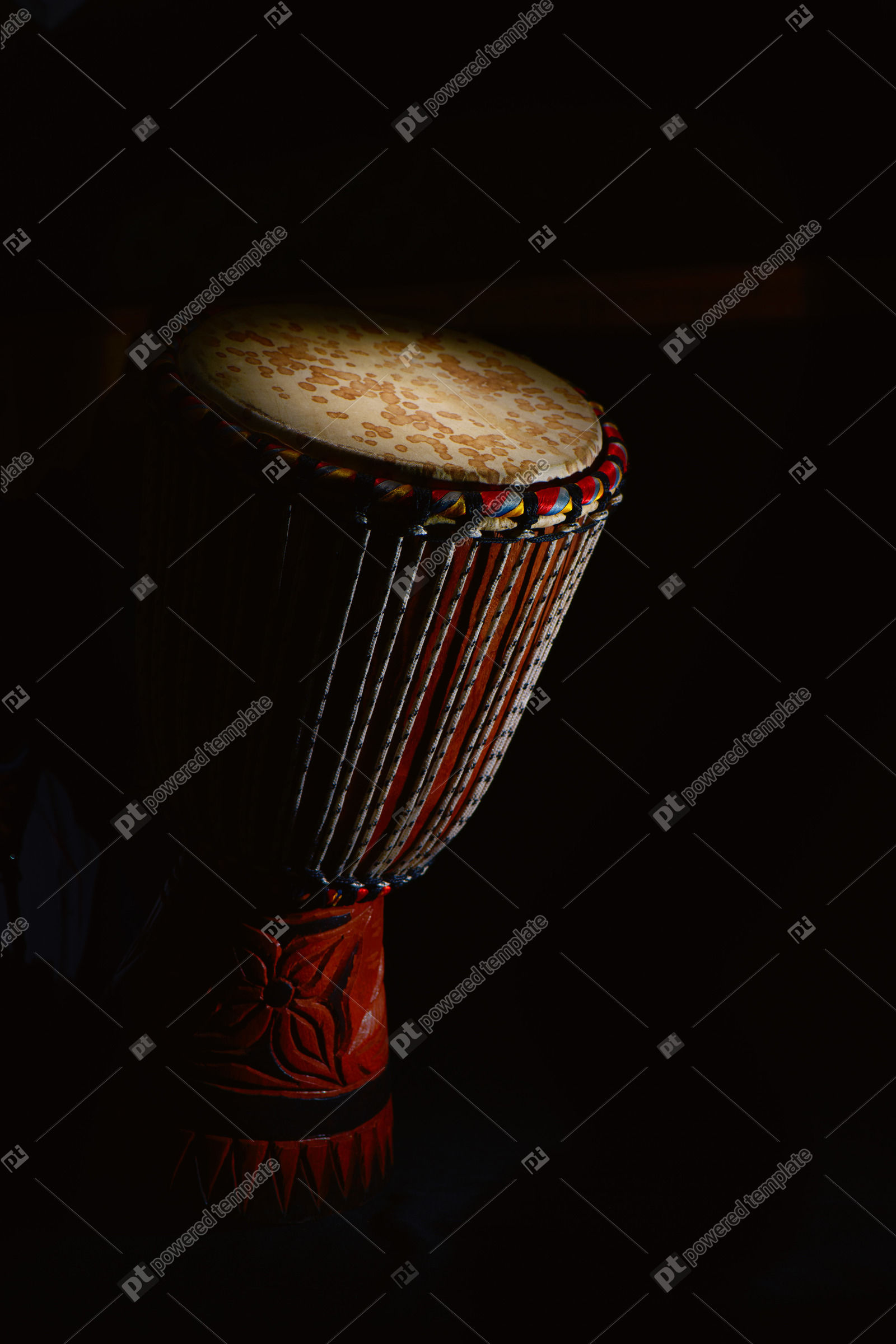 Djembe Percussion Partially Illuminated on a Black Background正版照片101019
